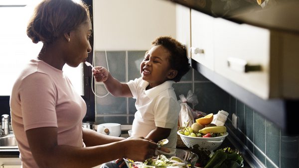 child feeding mother with cooking food in the kitchen