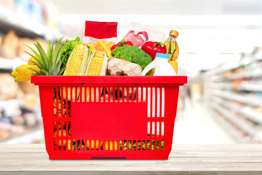 Shopping basket full of food and groceries on the table in supermarket